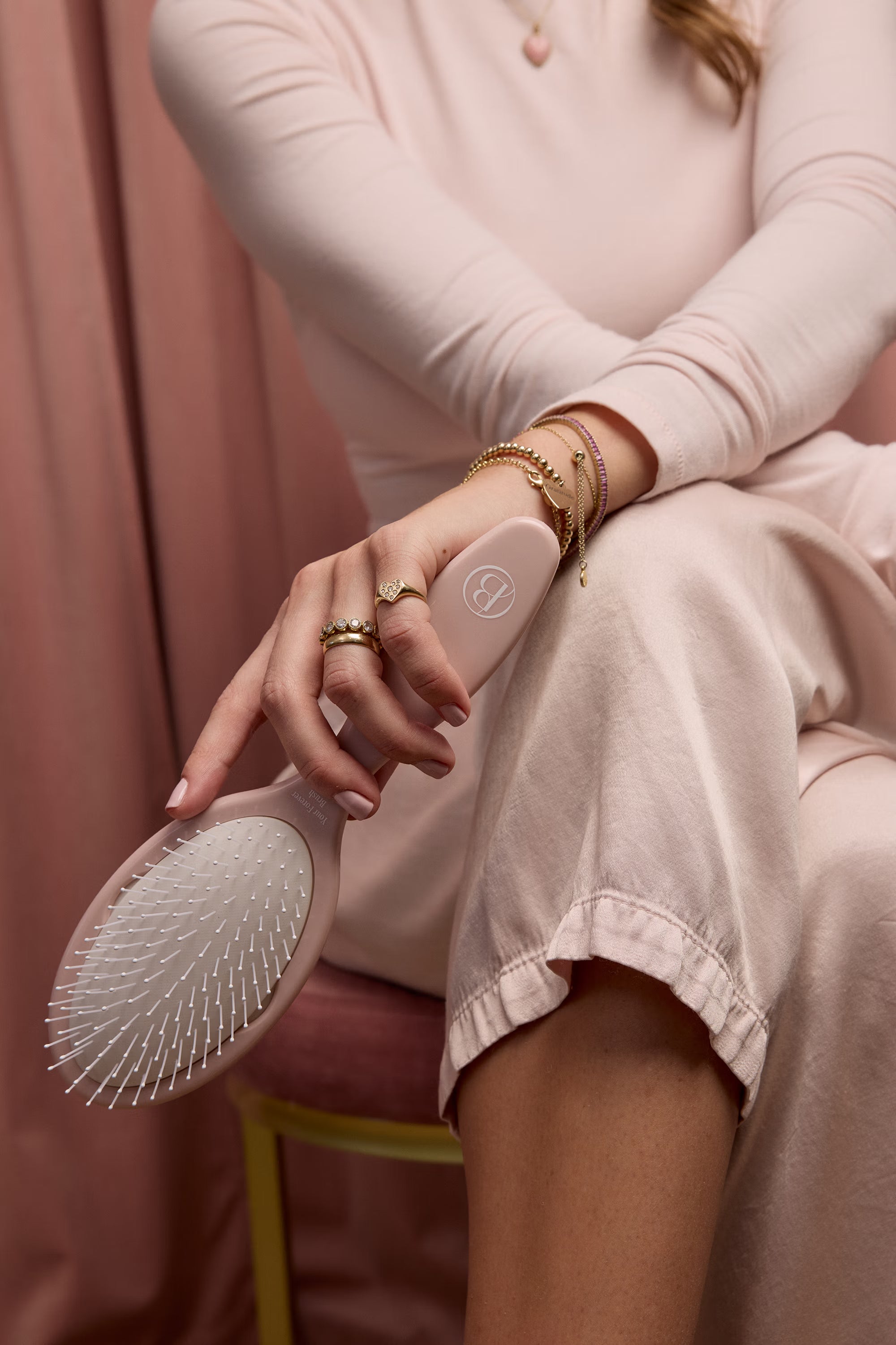 Person holding a pink hairbrush with a pink background
